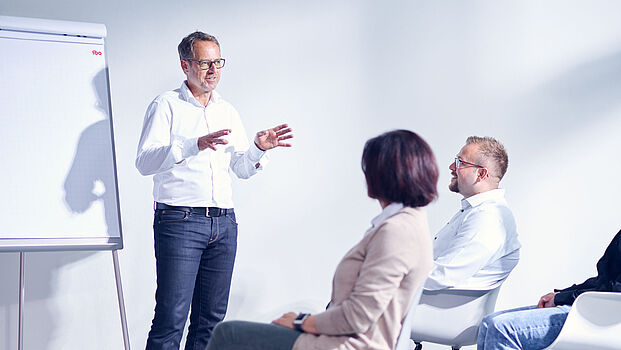 Trainer von ibo Akademie bei einer Weiterbildung am Flipchart vor Teilnehmern